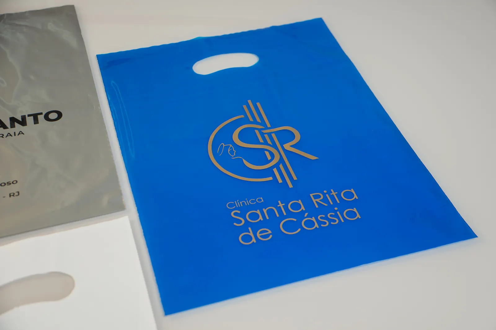 Sacola plástica azul personalizada Clínica Santa Rita de Cássia com alça vazada